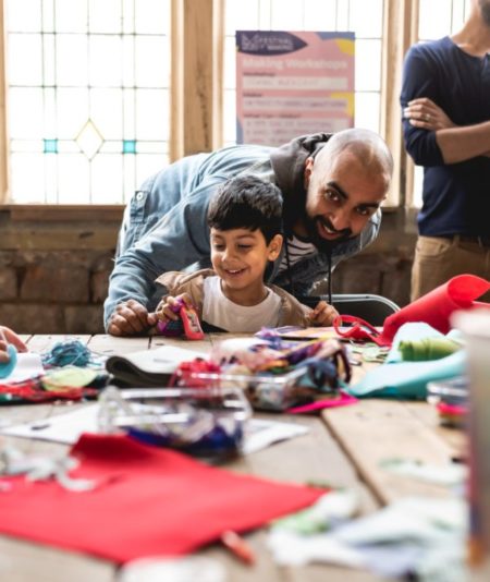 A boy and adult making something at the festival of making, surrounded by thread and felt