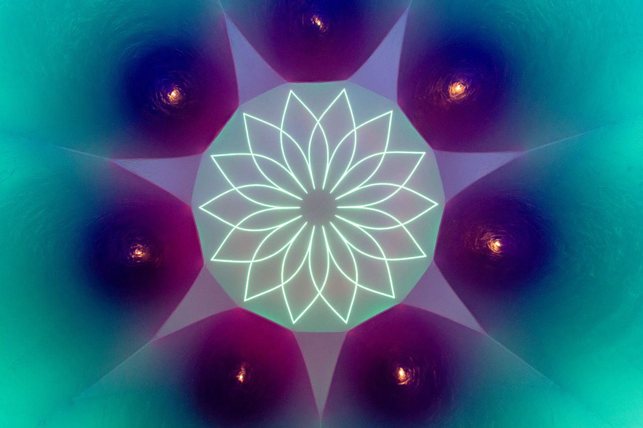 A geometric, glowing white flower pattern is centred against a teal and purple background, surrounded by eight circular, illuminated points arranged symmetrically. The image has a kaleidoscopic, abstract appearance.