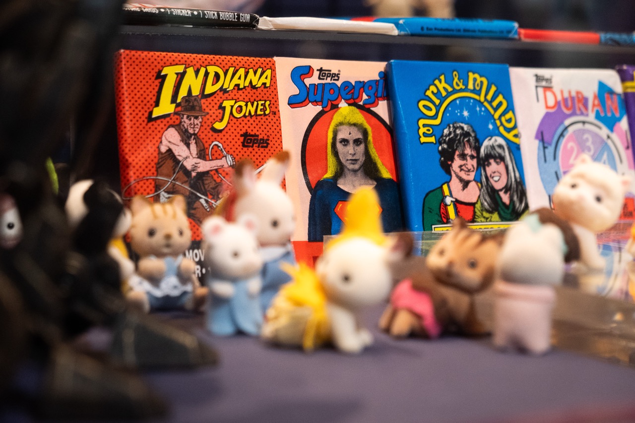 A display featuring vintage Indiana Jones, Supergirl, and Mork & Mindy trading cards, with small cat figurines in costume posed in front of the cards.