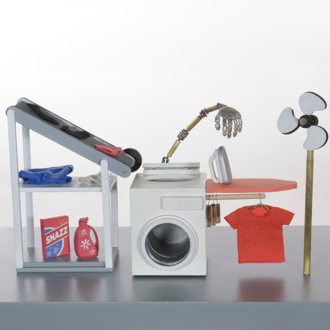 A whimsical laundry scene with a miniature washing machine, a conveyor belt for moving clothes, a robotic arm holding a shirt, laundry detergent, a fan, and folded clothes, all set against a plain background.