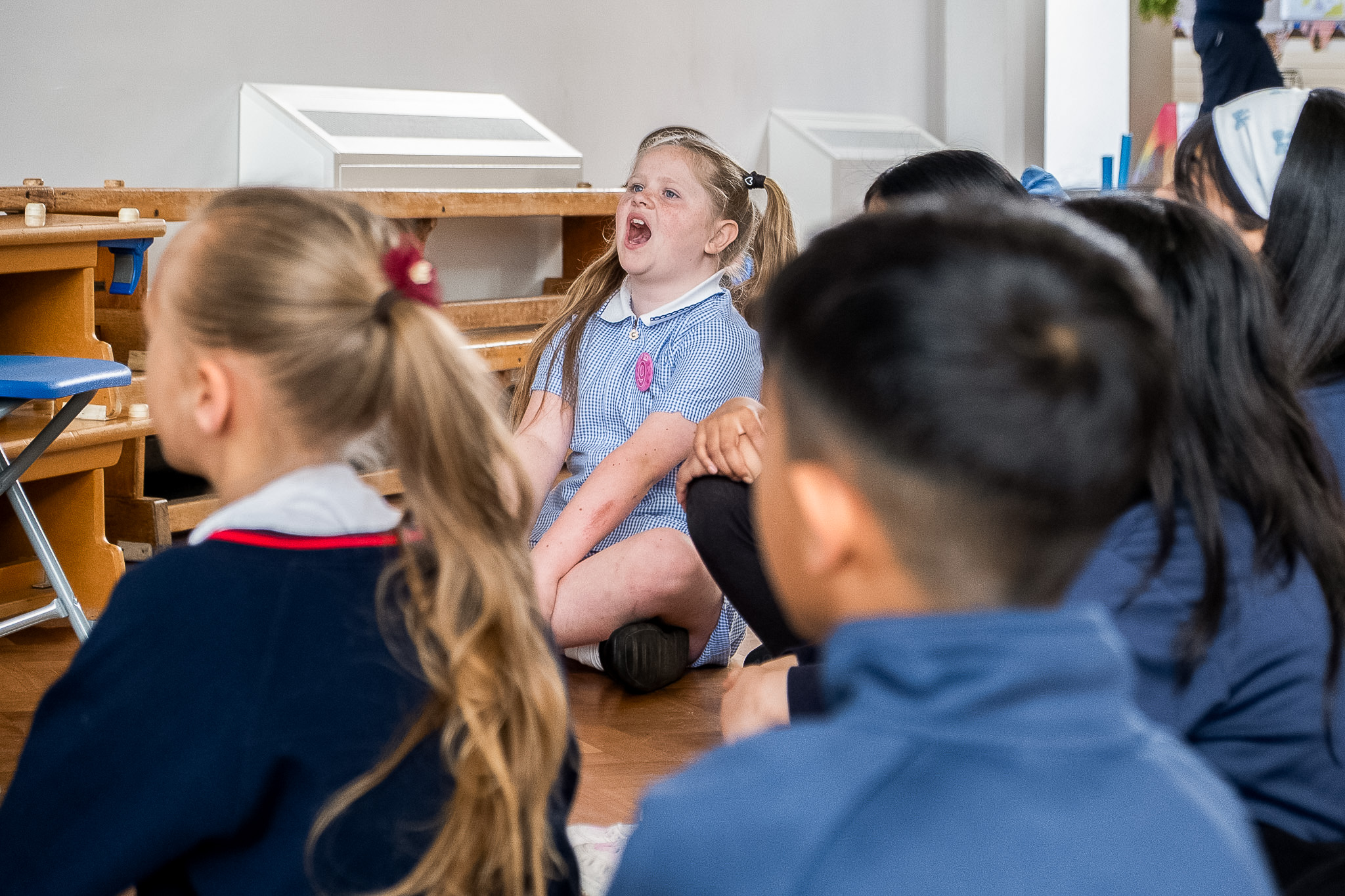 Group of children in school uniforms singing indoors.
