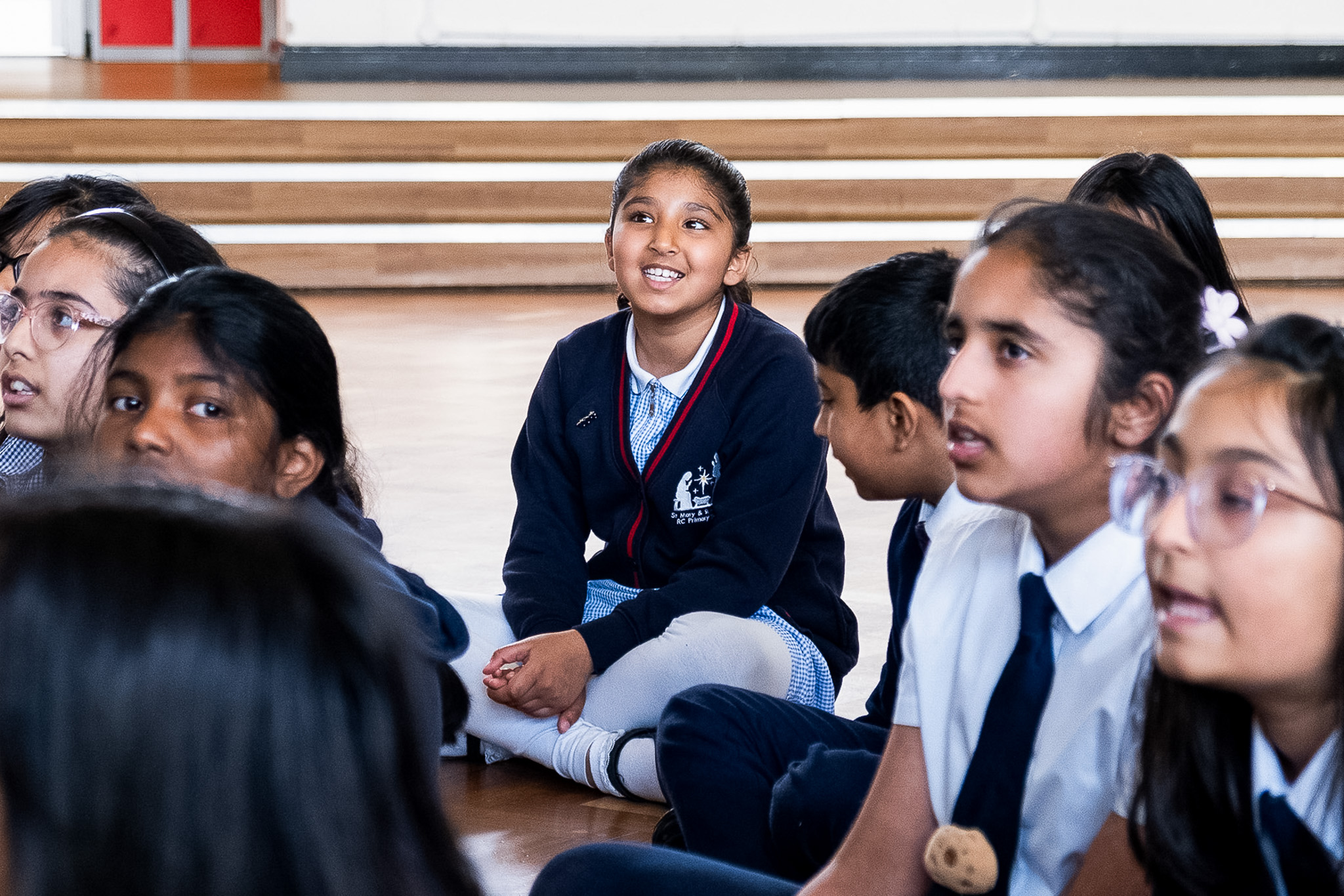 Group of children in school uniforms singing indoors.