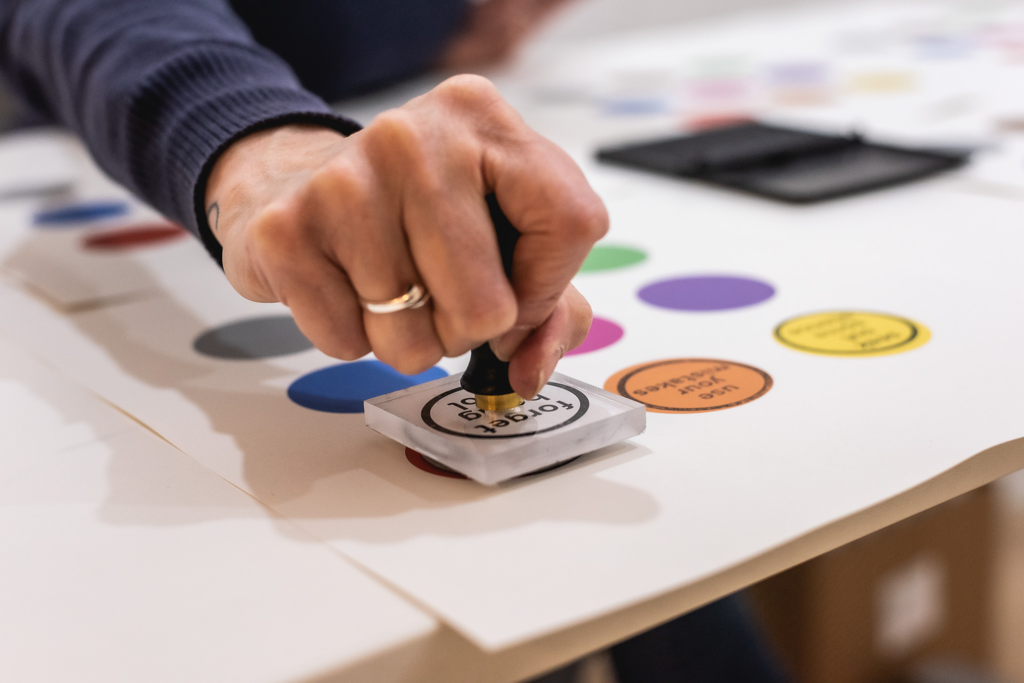 A person presses a round stamp onto a colourful chart with various circular stickers.