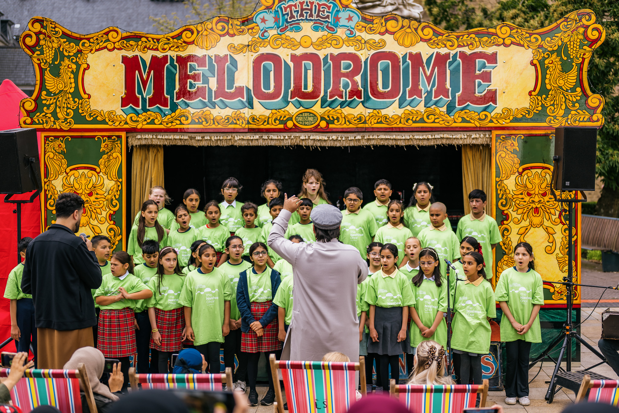 A choir of children in green shirts performs onstage at the colourful Melodrome.