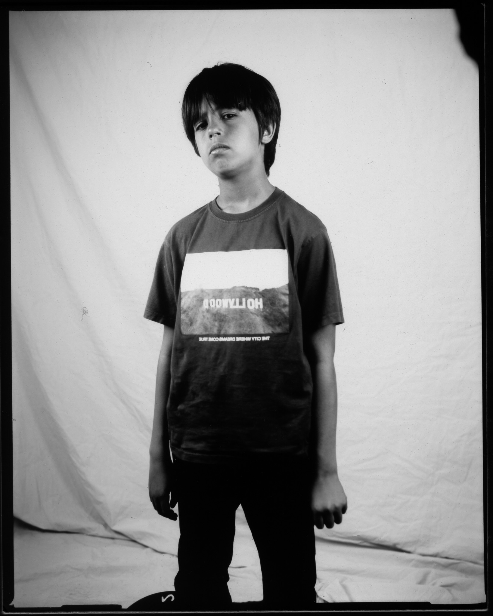 Child wearing a “Hollywood” T-shirt, confidently posing in a black and white photo.