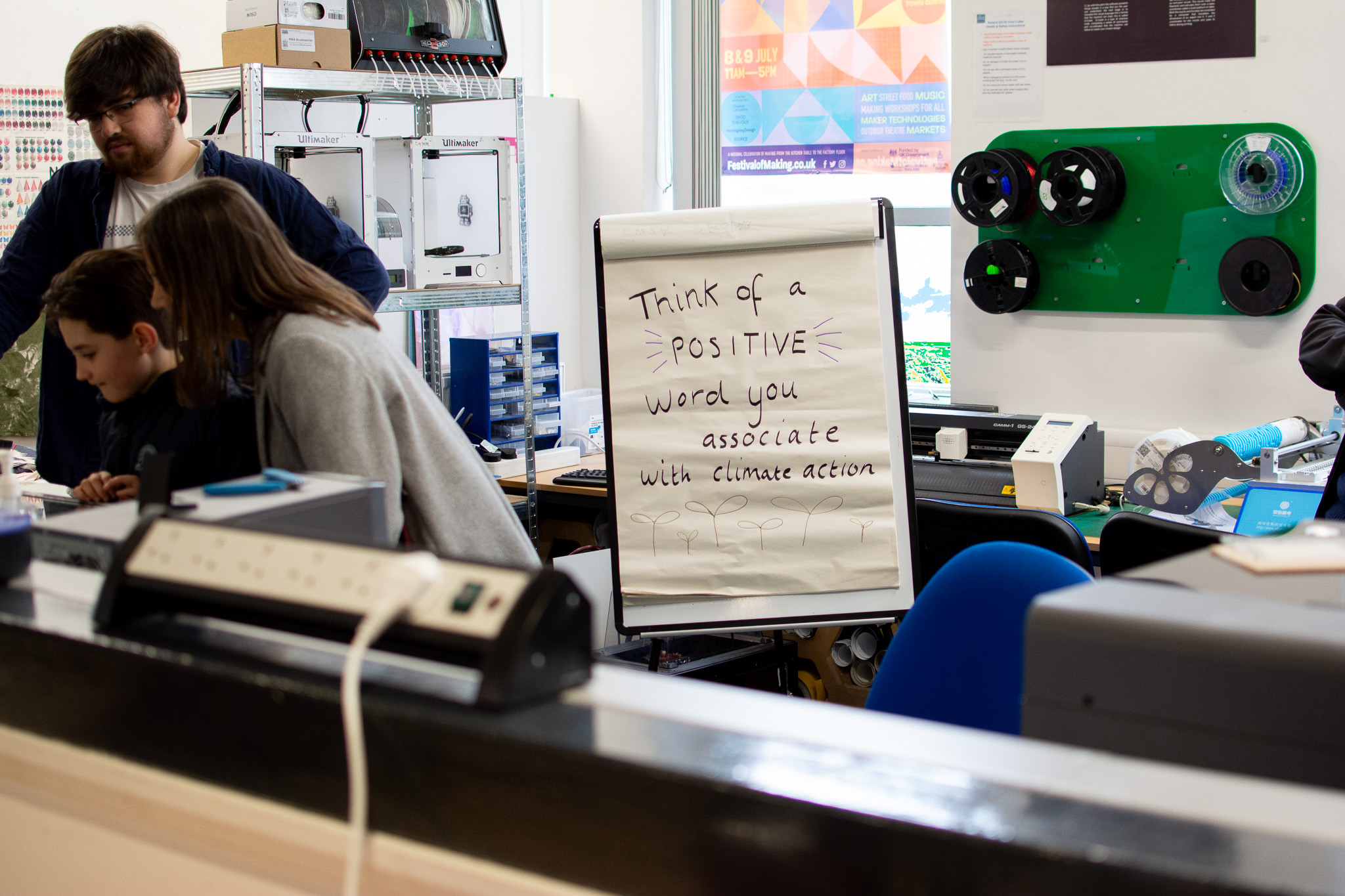 Workshop scene with people brainstorming climate action words on a flipchart. Shelves with tech equipment in the background.
