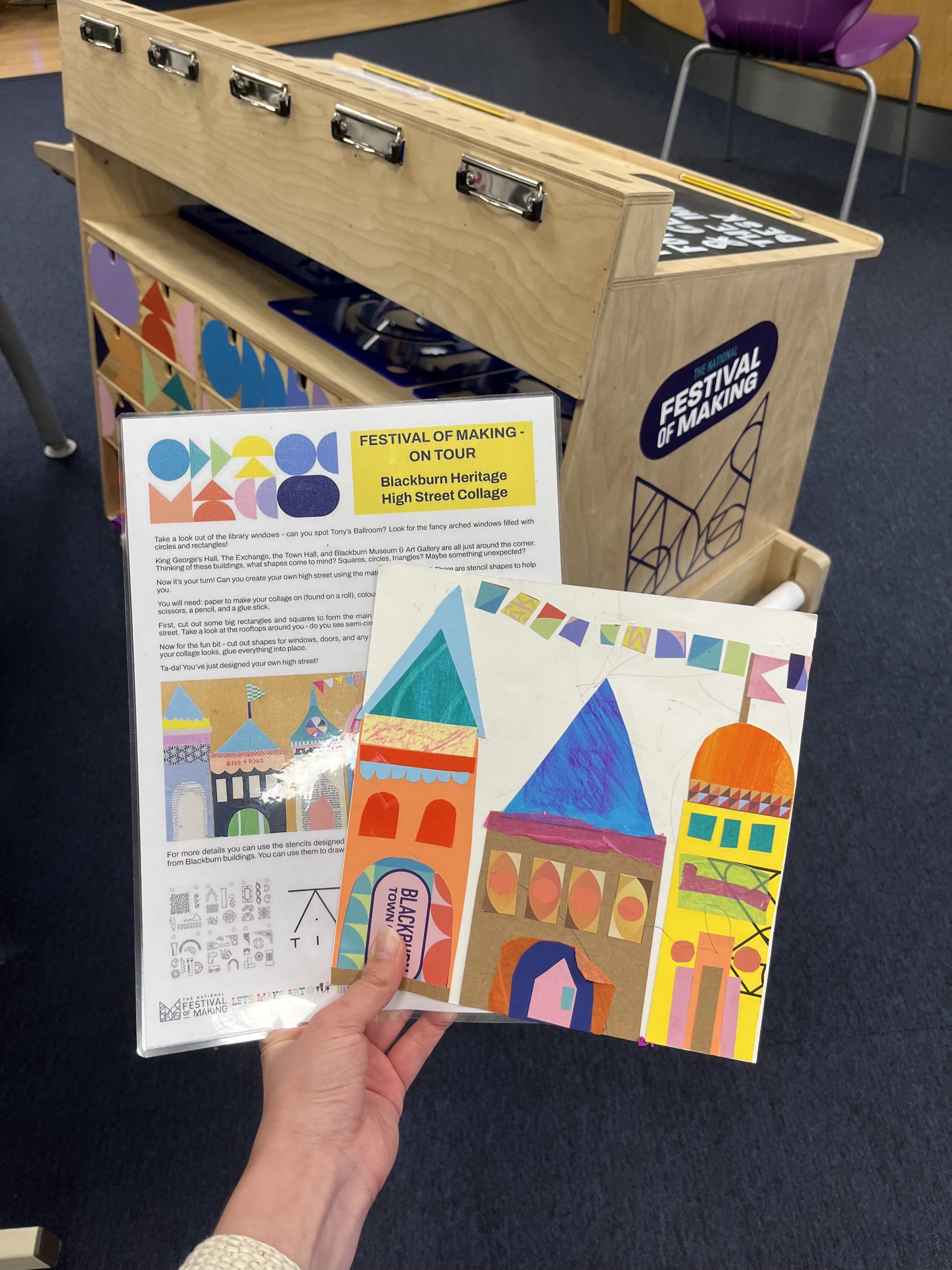 A hand holds a festival flyer and a colourful collage of buildings, including domes and arches, with bunting overhead. A sign in the background reads Festival of Making.