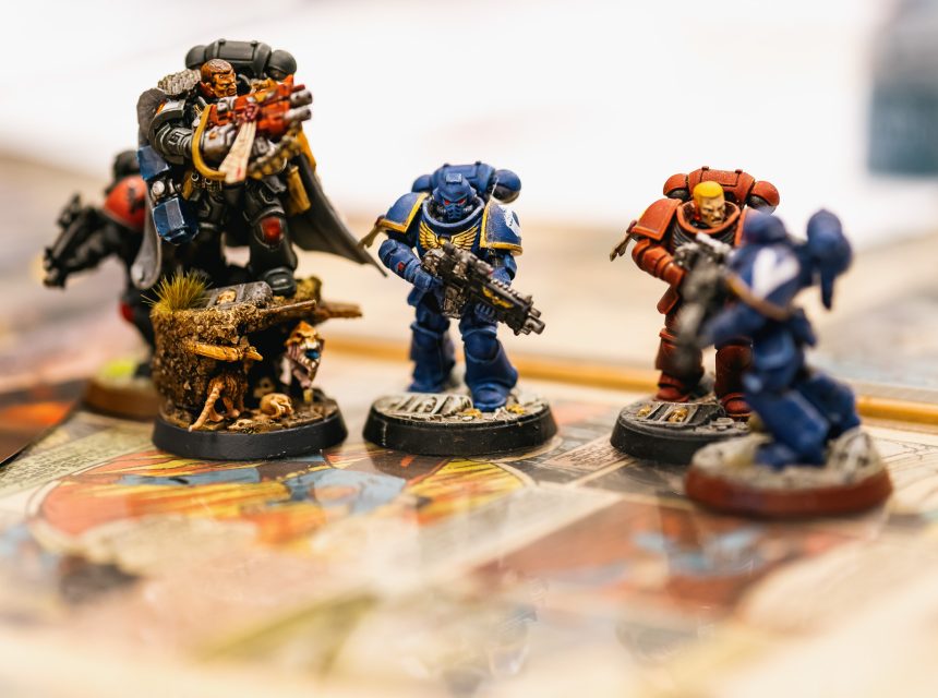 Close-up of detailed, painted miniature figurines in sci-fi armour, standing on a colourful board.