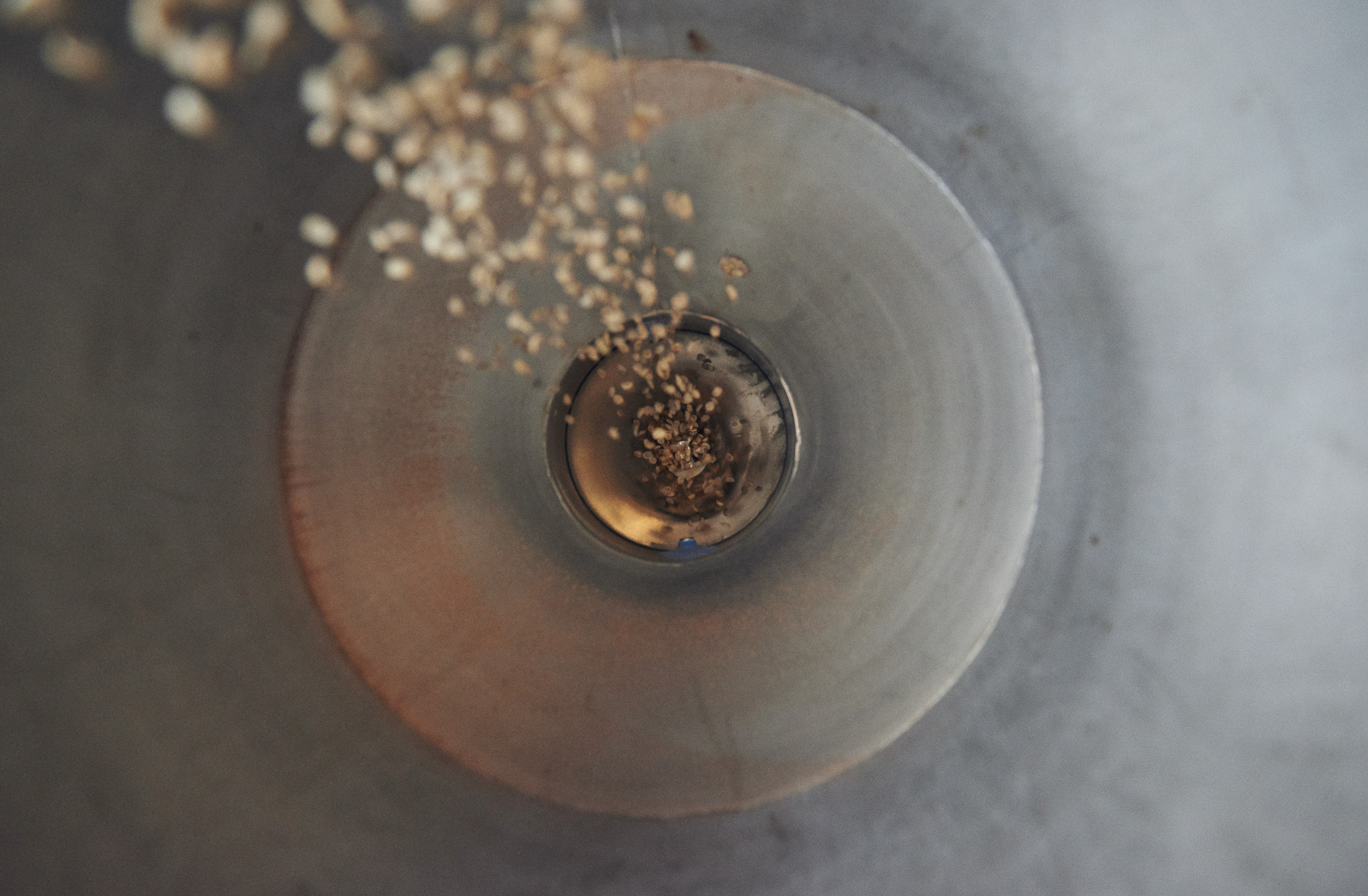Inside view of a metal funnel with grains falling into it, creating a spiralling motion.