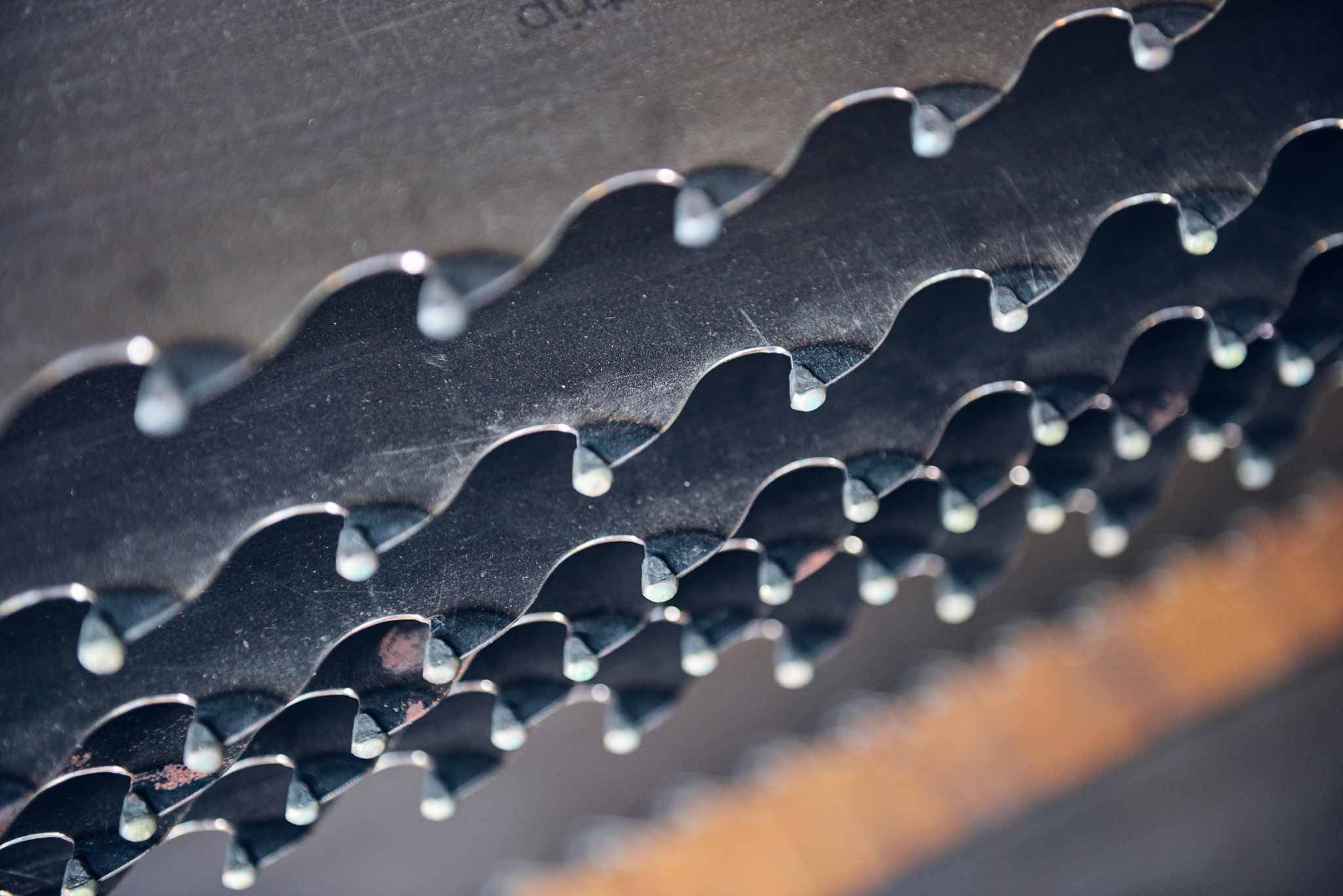 Close-up of a circular saw's serrated metal teeth, arranged in layered rows, creating a repeating pattern