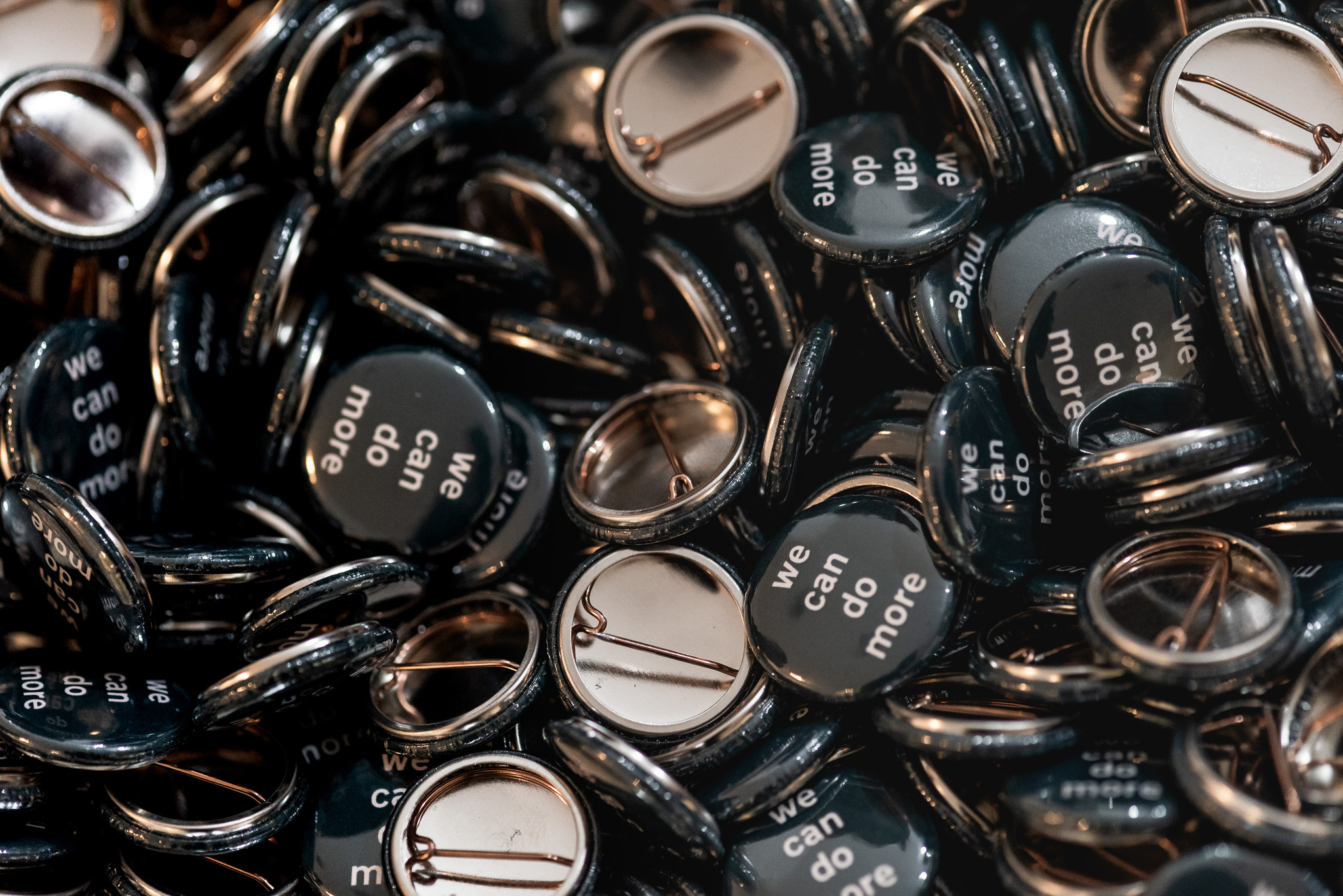 A close up of badges which say 'we can do more'.