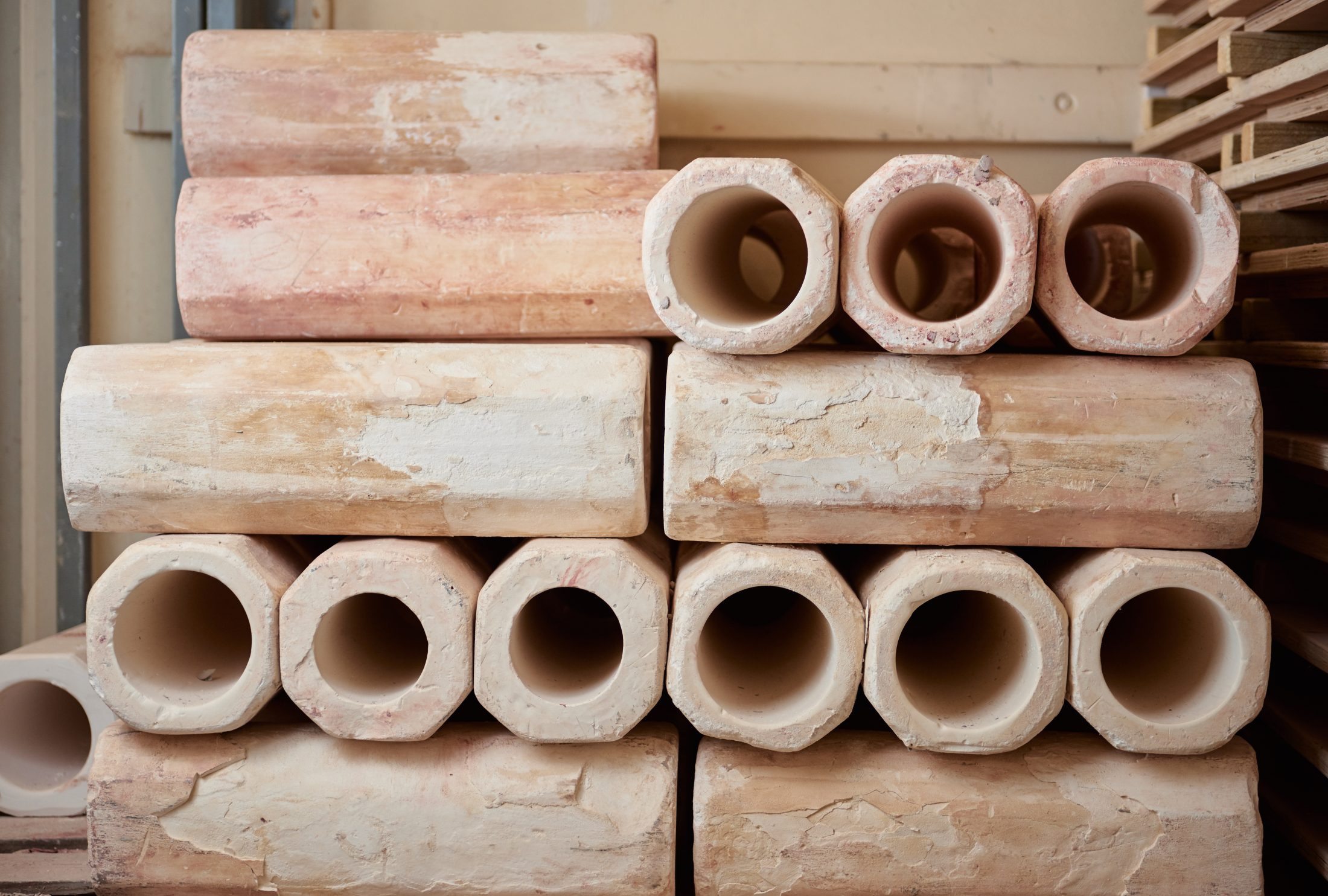 Stack of large, hollow clay pipes with a rough, uneven texture. The pipes are stacked in a neat formation.