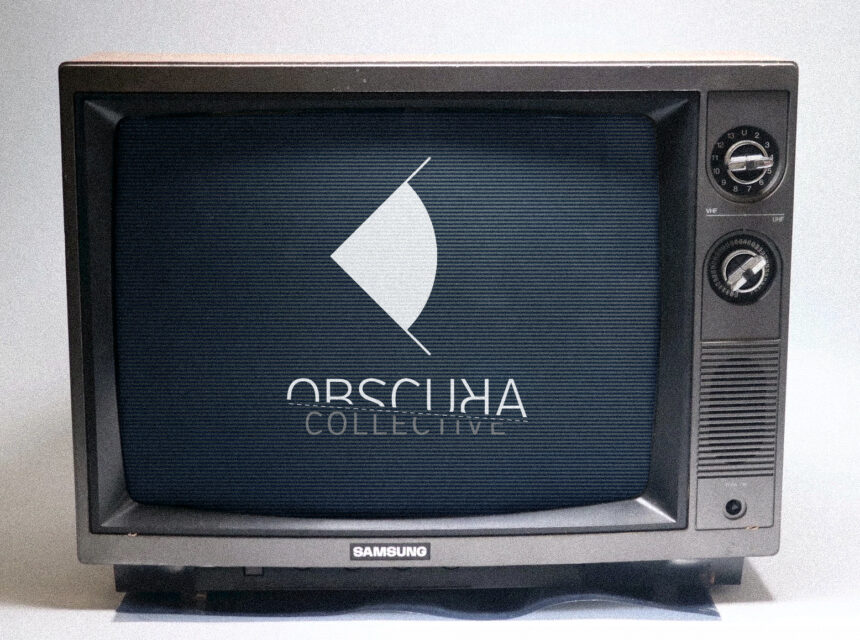 An old Samsung TV displays a logo with a white abstract shape above the words OBSCURA COLLECTIVE on a dark screen. The TV has dials on the right side.