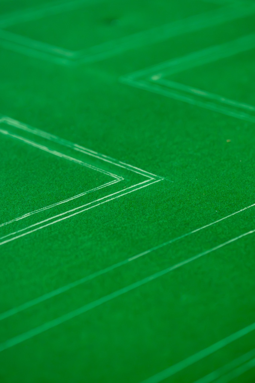 Close-up of a green sports pitch with white lines forming sharp angles and geometric patterns, possibly indicating part of a playing area or boundary markers.