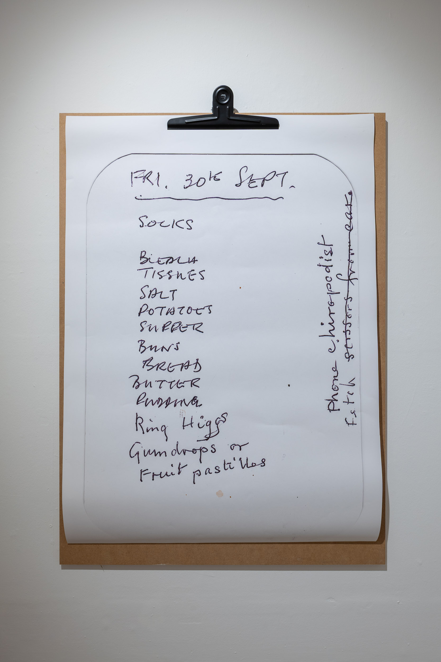 A handwritten shopping list on a clipboard includes items like socks, tissues, potatoes, butter, bananas, and jelly babies, with notes written in the margins.